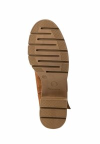 Bota de tobillo de ante marrón con suela de goma texturizada, que presenta ranuras horizontales y verticales para mayor agarre. Etiqueta de talla marcada como 37.