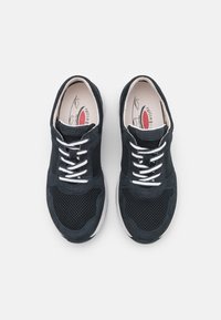 Schwarze Mesh-Sneaker mit Wildlederakzenten, weißen Schnürsenkeln, gepolsterten Zungen und einem weichen Innenfutter. Dicke Gummisohlen sorgen für Grip.