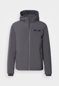 Giacca grigia con cappuccio e zip frontale, polsini elasticizzati e tasche laterali. Presenta una toppa con logo nera sul petto. Tessuto elegante e liscio.