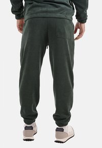 Pantaloni jogger verdi in morbido tessuto con finitura testurizzata, dotati di una vita elasticizzata, polsini e una singola tasca posteriore.