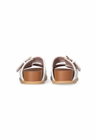 Sandales blanches avec un design de brides, talon épais marron et semelles texturées. Détail de boucle ajustable sur le côté pour un meilleur ajustement.