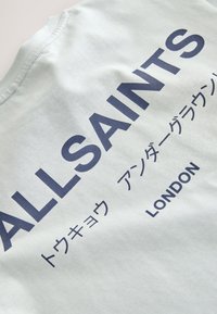 Weißer Stoff mit marineblauem Text „ALLSAINTS“, japanischen Schriftzeichen und „LONDON“, gedruckt in einer fetten Großschrift.