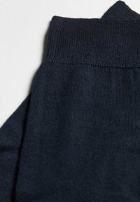 Mørkeblå strikkede leggins med en ribbet talje. Teksturen er glat med ensartet syning og ingen synlige mønstre eller accenter.
