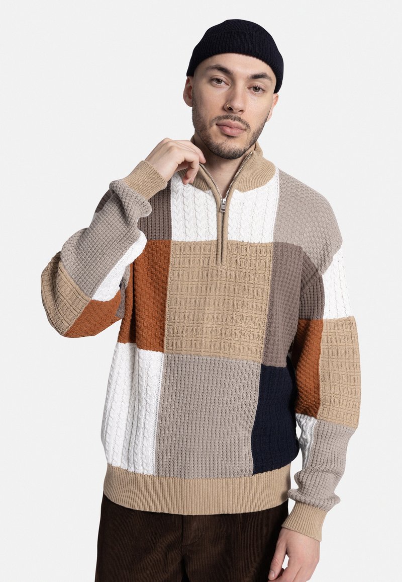 Sudadera de punto con cremallera que presenta un diseño de patchwork en beige, marrón, azul marino y blanco. Tela texturizada con puños y dobladillo acanalados.