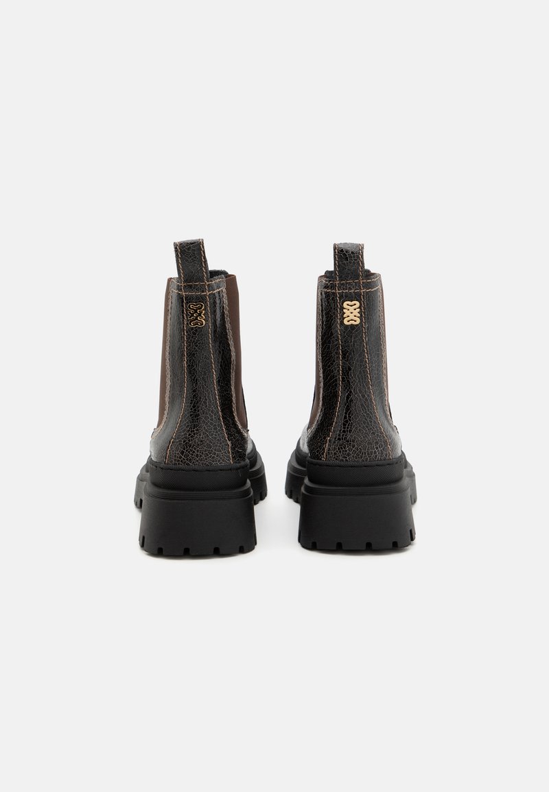 Schwarze und braune Stiefeletten aus genarbtem Leder mit elastischen Seitenpanelen und einer dicken, strukturierten Gummisohle. Goldene Markenverzierung an der Ferse.