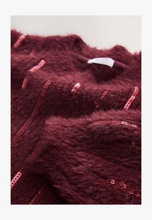 Bordowy sweter z dzianiny o puszystej fakturze, ozdobiony pionowymi paskami różowych cekinów. Etykieta widoczna przy dekolcie.