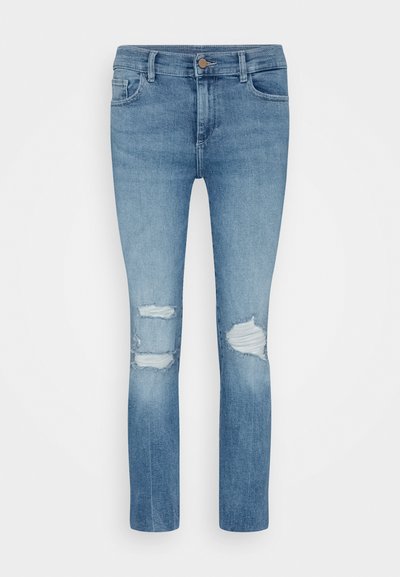 Jeans de denim azul claro com um corte slim, apresentando áreas de joelho desgastadas e um desbotamento sutil ao longo da peça. Design clássico de cinco bolsos.