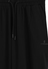 Pantalones jogger de algodón negro con cintura elástica y cordón ajustable. Presentan un sutil logo "FREDDY" impreso en gris en la parte inferior derecha.