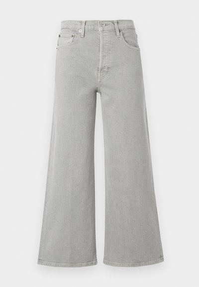 Svijetlosivi traperice širokih nogavica, visokog struka, s prednjim džepovima i zatvaranjem na gumbe. Glatka tekstura s minimalnim dizajnerskim detaljima.