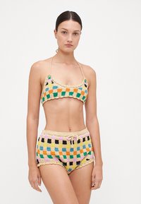 Ensemble de bikini au crochet en carrés multicolores. Le haut possède des bretelles fines ; le short taille haute présente un ourlet en forme de coquille et une taille avec cordon de serrage.
