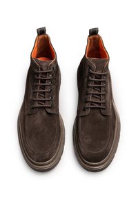 Botas de tobillo de ante marrón con forro naranja, punta redondeada y suela de goma gruesa. Presenta cordones en contraste y detalles de costura.