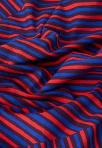 Βαμβακερό ύφασμα με κυματιστό μοτίβο από κόκκινες, μπλε και σκούρες μπλε ρίγες, δημιουργώντας υφή με ανάγλυφη εμφάνιση. Οι ρίγες διαφέρουν σε πλάτος.