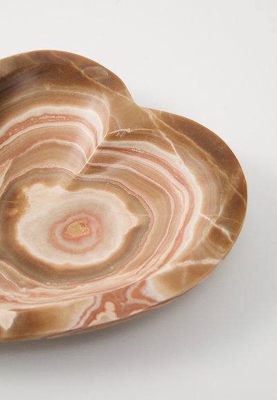 Farfurie în formă de inimă, realizată dintr-o piatră marmorată în nuanțe de crem și maro, având cercuri concentrice și o suprafață netedă, lucioasă.