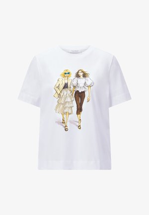 Zwei modische Frauen gehen, eine mit Sonnenbrille, mehrlagigem Rock und Blazer, die andere mit Oberteil mit Puffärmeln und gekürzten Hosen, auf einem weißen Hemd.