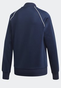 Námořnická modrá sportovní bunda s dlouhým rukávem, s bílým lemováním na raglánových rukávech, manžetami s žebrovaným vzorem a žebrovaným pasem, zobrazena zezadu.