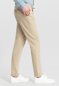 Vaaleat chinot, joissa on slim fit -malli, valmistettu puuvillakankaasta. Omistaa nyörikiristyksen vyötäröllä ja takataskut, yhdistetty valkoisiin tennareihin.