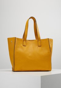 Gul læder tote taske med en tekstureret overflade, to solide håndtag og kontrasterende sort trim langs kanterne. Ingen synligt hardware.