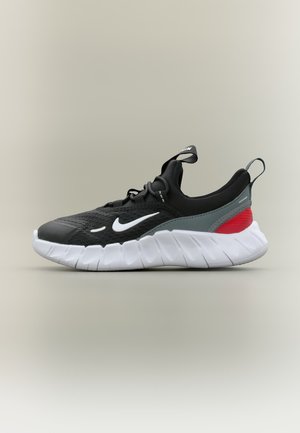 Baskets Nike noires et grises avec virgule blanche, accent rouge au talon, semelle blanche épaisse et languettes à tirer sur la languette et le talon.