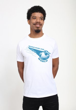 White cotton t-shirt featuring a blue graphic design with a globe and the text "WINGS OVER THE WORLD" in bold, stylized font.