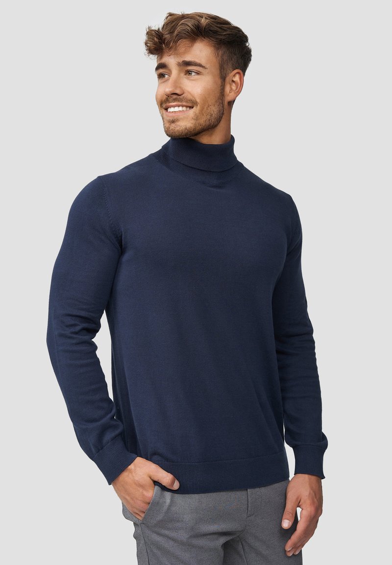 Marineblå turtleneck-genser, lett strikket, tettsittende design, lange ermer, ribbestrikket krage og mansjetter, jevn tekstur, enkel stil.