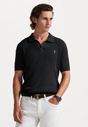 Melnas īsām piedurknēm polo krekls ar ribotu tekstūru un apkakli. Tam ir neliels izšūts logos kreisajā krūtī, valkāts ar baltām biksēm.