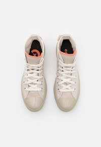 Höga sneakers i beige kanvas med glänsande tån, vita snören och orangea detaljer. Gummisula med cirkulär logotyp på insidan.