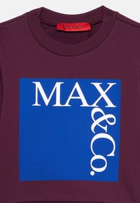Felpa bordeaux con una grafica rettangolare blu che presenta il testo "MAX & Co." in grassetto bianco. Texture del colletto a costine.