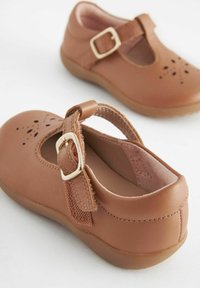 Brązowe skórzane buty z okrągłym noskiem, wyciętym wzorem i brązowym paskiem z złotą klamrą. Miękka podszewka i gumowa podeszwa.