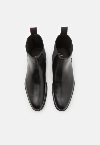Black leather ankle boots with a smooth finish, elastic side panels, and pull tabs, featuring a minimalist design and pointed toe shape.