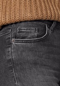 Zwarte denim jeans met een standaard vijf-pocket ontwerp, met een subtiele structuur en contrasterende stiksels langs de naden.