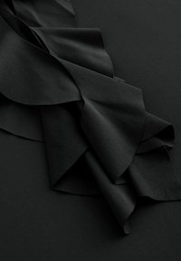 Black fabric featuring layered satin ribbons with a smooth texture and elegant drape, arranged in a flowing, dynamic manner.
