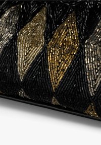 Primer plano de una tela negra con bordado de cuentas doradas y plateadas en patrones geométricos de diamante.
