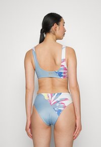 Biquíni de duas peças com base azul, apresentando um padrão floral em rosa, amarelo e branco. Textura suave, alças largas e detalhe com o logotipo da Roxy.