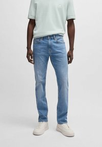Herrens ljusblå jeans med rak passform, med klassiska fickor och kontrasterande sömmar, tillsammans med en avslappnad mintgrön t-shirt.