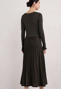 Abito a maniche lunghe in maglia a coste metallica scura, con un corpino aderente e una gonna a pieghe svasata. Presenta un scollo rotondo e polsini arricciati.