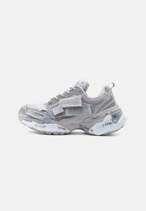 Chunky gray and white sneaker with mesh, fabric patches, thick sole featuring handwritten text and measurement markings on a white background.