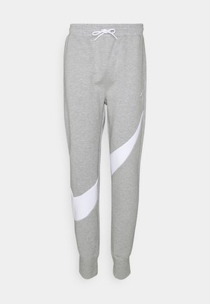 Jasnoszare spodnie dresowe z białym zakrzywionym paskiem na nogawkach, elastycznym pasem z białym sznurkiem oraz ściągaczami przy kostkach.