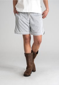 Gray mesh shorts with a drawstring waist, featuring a textured surface and white trim, paired with brown knee-high boots.