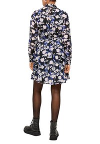 Bloemrijke jurk met een zwarte achtergrond, met blauwe en blush patronen, lange mouwen, cinched taille en een uitlopende rok. Zwarte enkelboots.