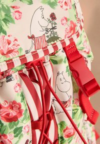 Színes anyagú hátizsák virágmintákkal rózsaszín és zöld színben, Moomin karakterekkel, piros pántokkal és húzózárral.