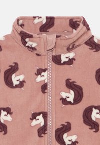 Fleece jumpsuit i myk rosa, med et mønster av hvite og brune enhjørninger. Hel glidelås foran og høy krage for varme.