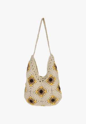 Sac à main crocheté en crème avec des motifs de tournesol en jaune et marron. Il présente une forme souple et une bandoulière unique.