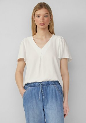 Haut blanc à manches courtes avec un décolleté en V et une texture douce, associé à un pantalon en denim à taille élastique de couleur bleu clair.