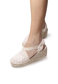 Beige espadrille wedge sandaalit, joissa on virkatut yläosat, joustava nilkkaremmi ja juuttikangas päällystetty pohja. Sisältää koristeellisen sivuaksentin.