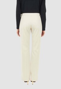 Pantaloni a vita alta di colore crema con righe verticali, dotati di un taglio dritto e di una texture in tessuto liscia.
