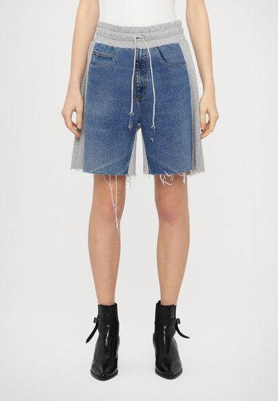 Shorts en denim avec un ourlet effiloché et une superposition en jersey gris à la taille, dotés d'une fermeture ajustable par cordon et de poches avant. Bottes noires à la cheville.