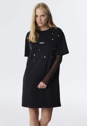 Vestido negro con mangas cortas, con adornos plateados. Las mangas de malla texturizada añaden contraste. Logos exhibidos en la parte frontal.