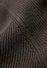 Tela marrón oscuro con un patrón acanalado texturizado, que muestra una costura intrincada y diferentes anchos en las líneas horizontales.