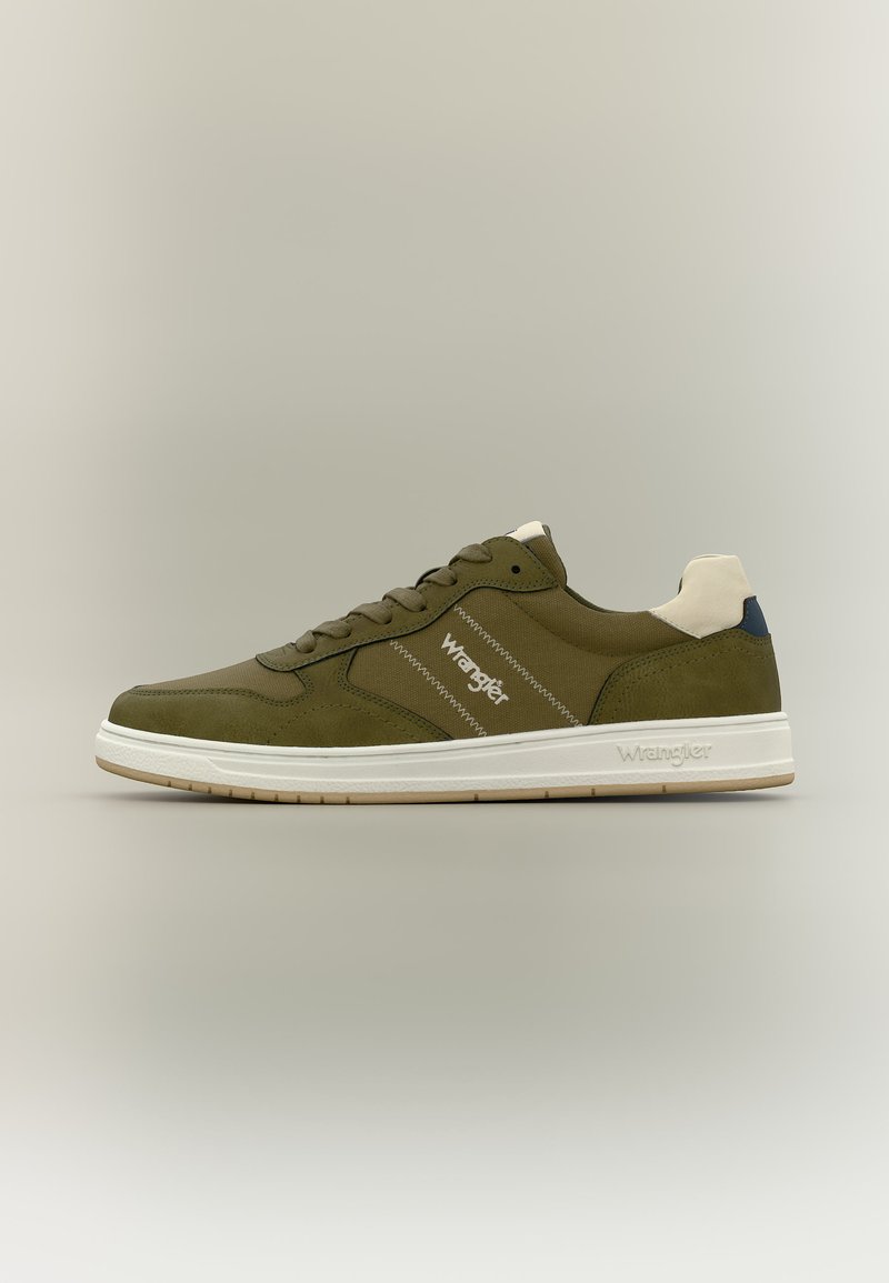 Oliivirohelised madala säärega tennised valge tallaga, paeltega ja "Wrangler" logo küljel ning taldal, neutraalse taustaga.