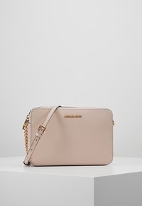 Ljusrosa lädercrossbody-väska med rektangulär form, guldhardware, justerbar axelrem och en logotyp på framsidan.
